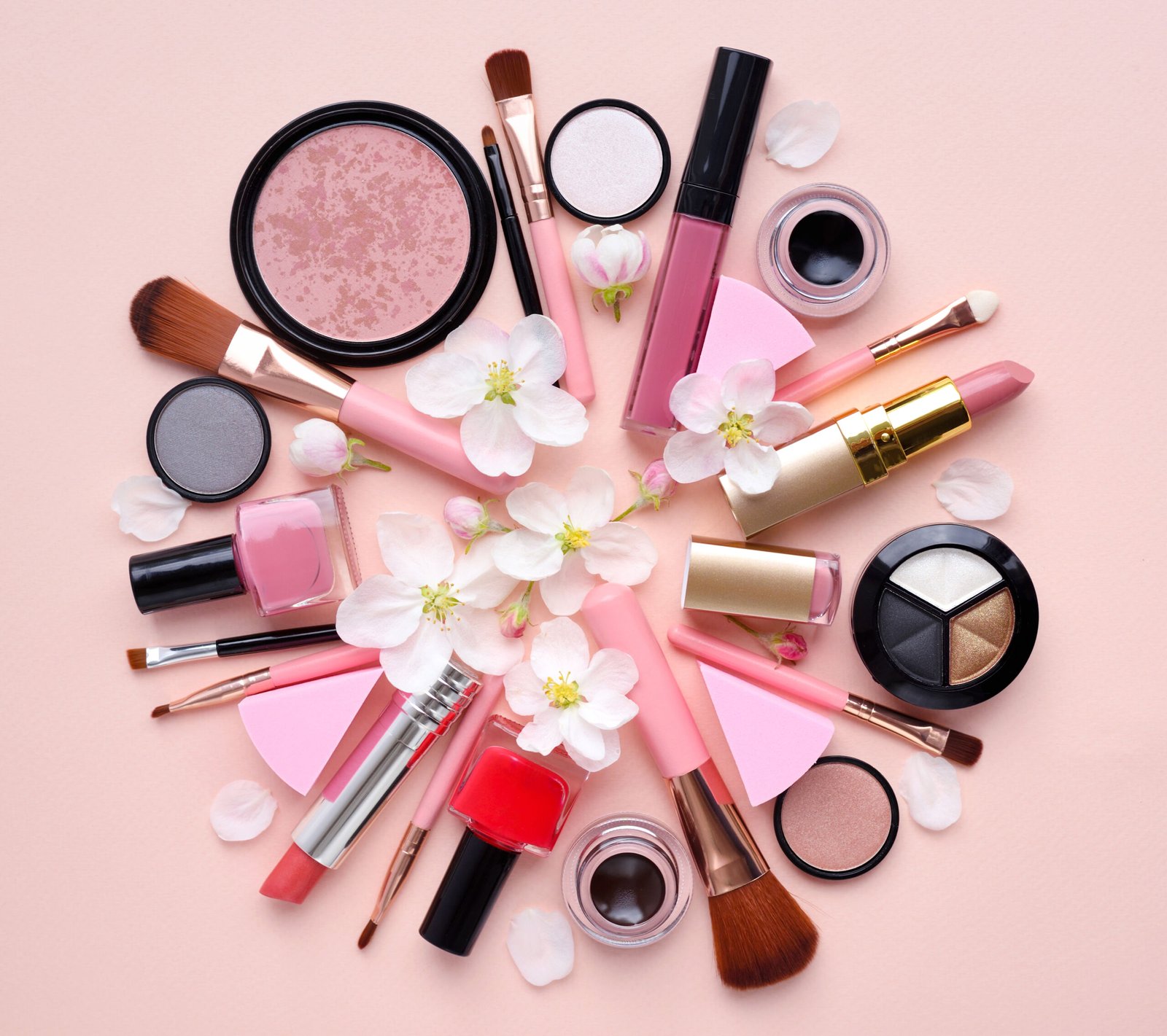 Decorative cosmetics with apple blossom on a pastel pink background with empty space. Top view